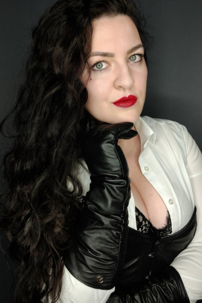 OHRgasmus erotische Hypnsoe Lady Hypnotica dominantes Bild, lange, schwarze Lederhandschuhe, tiefer Ausschnitt, lange schwarze, wellige Haare, rote Lippen